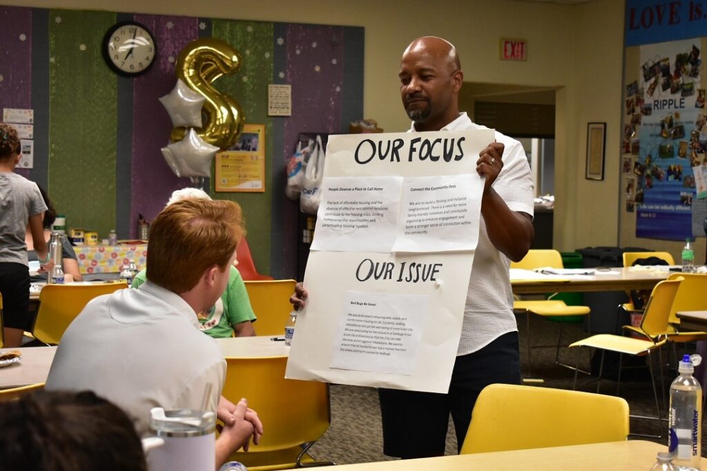 Cohesion Network - instructor holding up a "our focus, our issue" posterboard