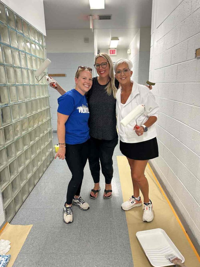 3 Women United volunteers pose with paint rollers