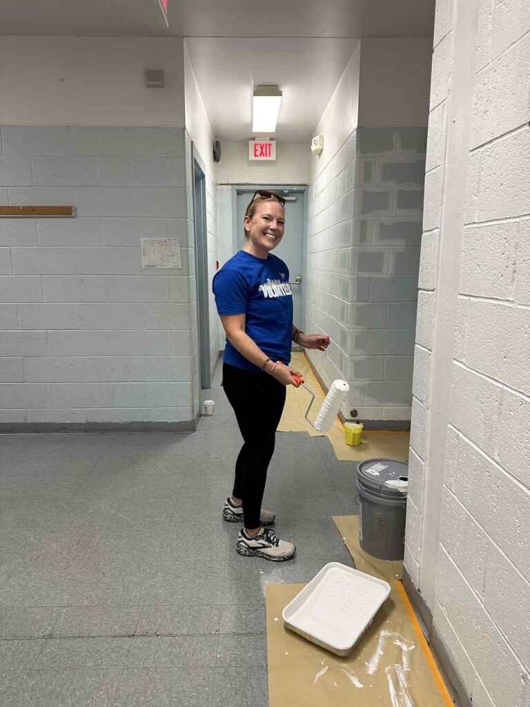 Women United member posing while painting a wall