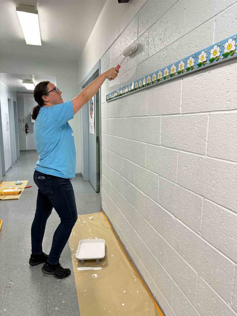 Women United volunteer painting a wall