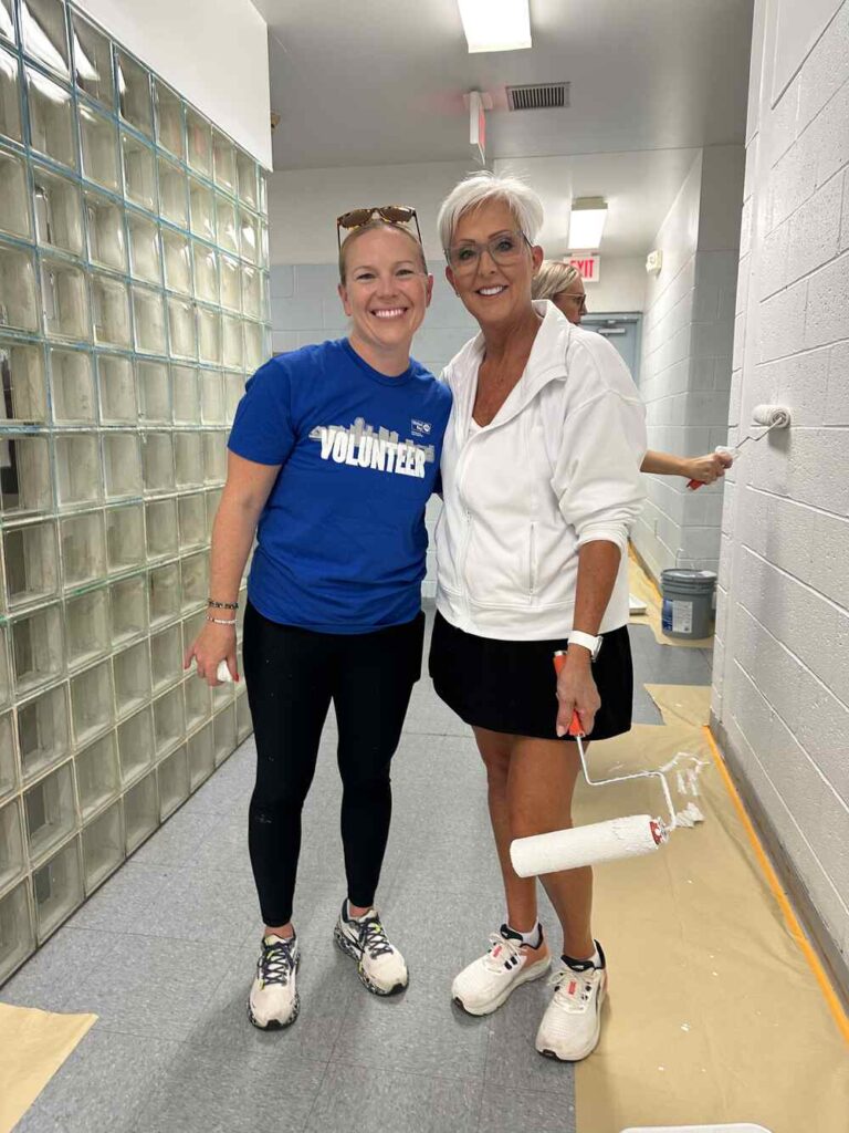 2 Women United volunteers pose with paint rollers