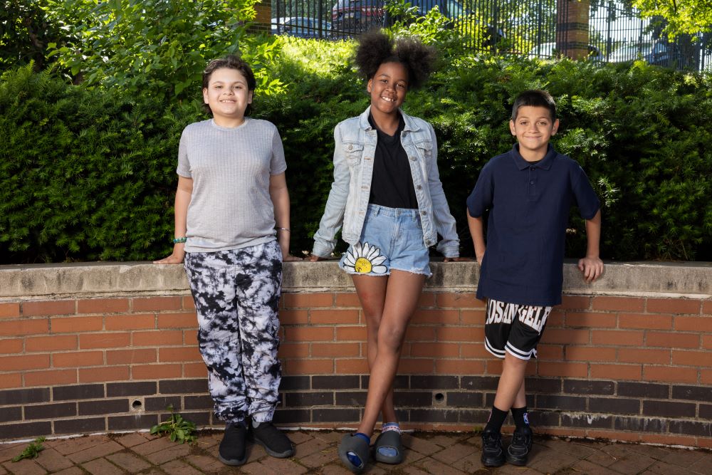 three students standing at a brick wall at Sheridan Elementary School in Allentown