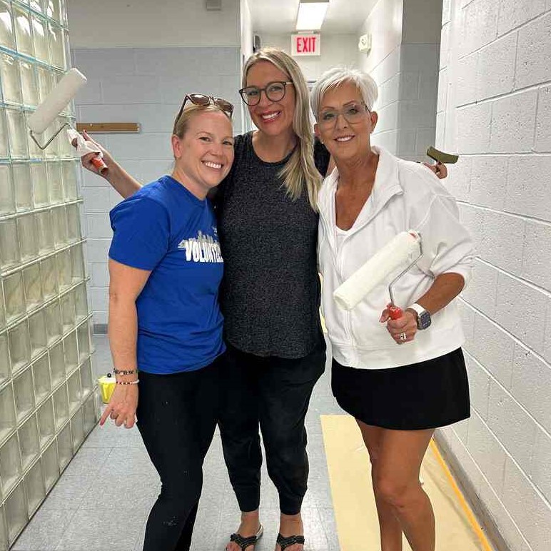 3 Women United volunteers pose with paint rollers